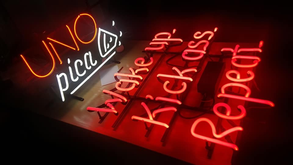 Red and white illuminated sign components arranged on a workshop table